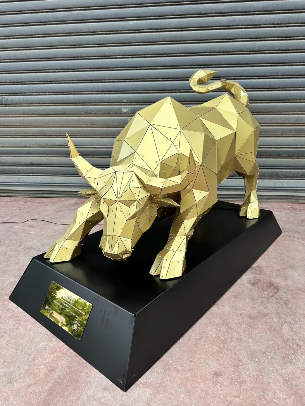 Escultura de toro metálico dorado en posición de carga